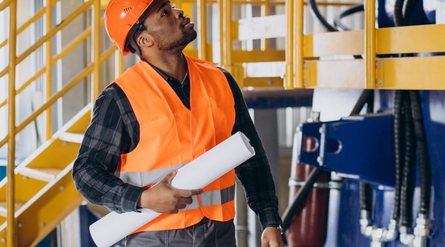 African american worker standing in uniform wearing a safety hat in a factory